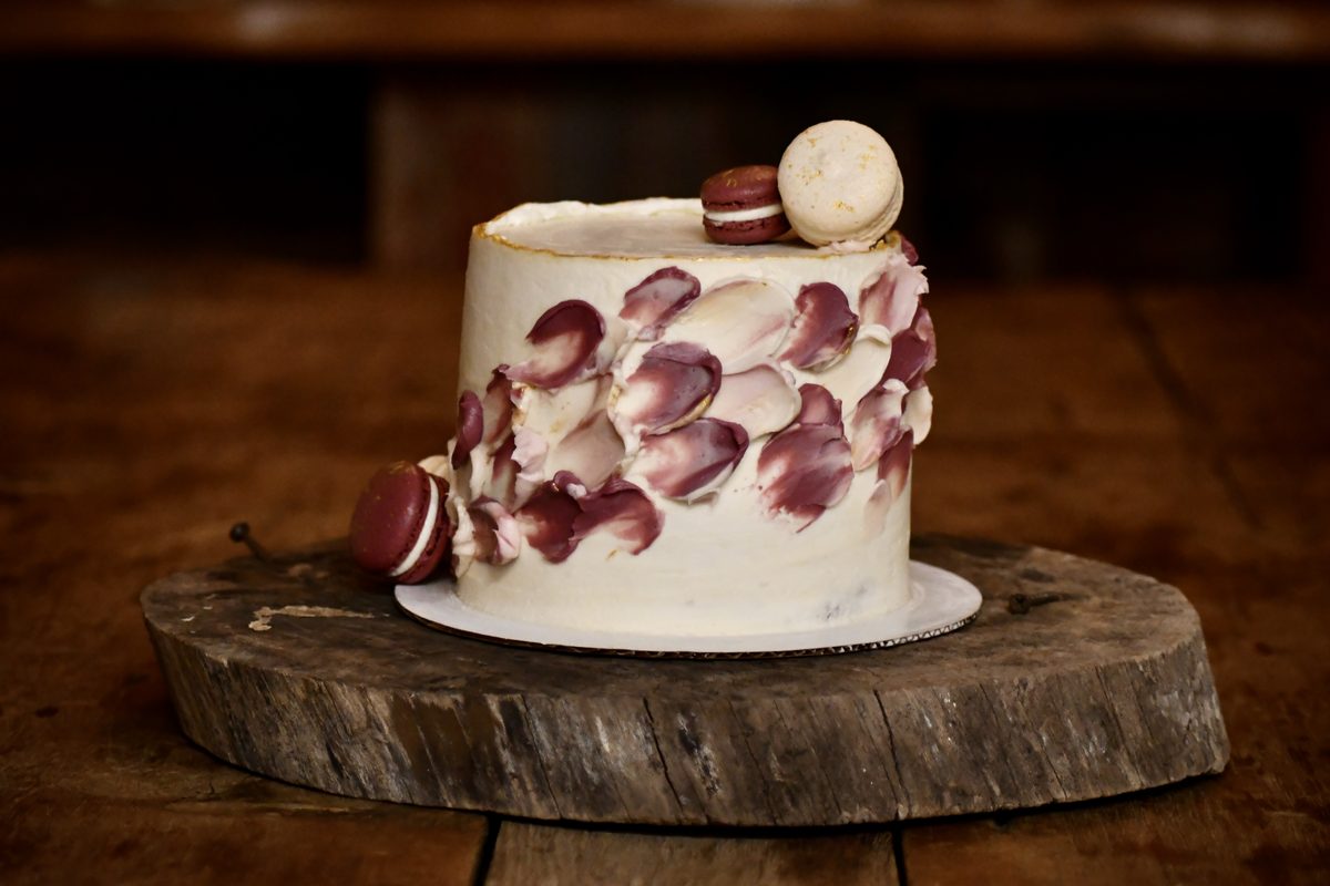 White wedding cake with burgundy petal detail and macarons